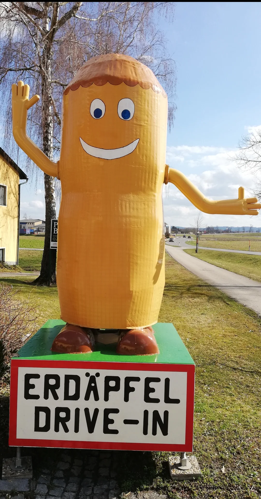 Große gemalte Erdapfel-Figur am Straßenrand, darunter die Tafel Erdäpfel Drive-In