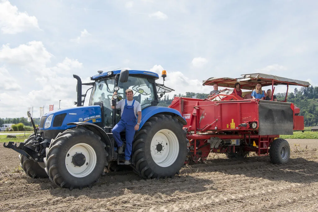 Traktor mit angehängter Kartoffel-Legemaschine auf dem frisch gezogenen Acker